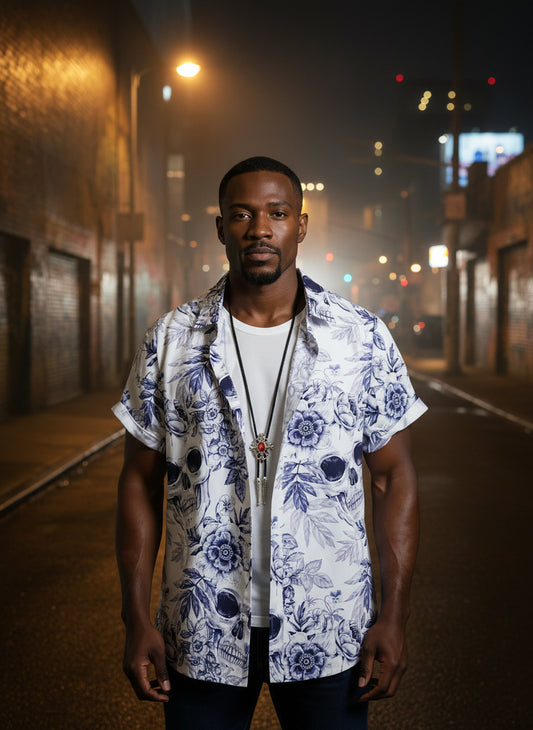 Man wearing a white shirt with blue floral and skull pattern on a white background